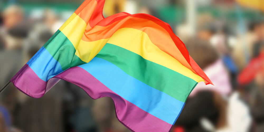 Gay Pride Flag. Blurred background of people crowd